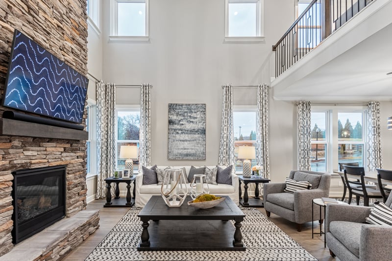 great room with two story ceilings, a stone fireplace, sofa, and area rug