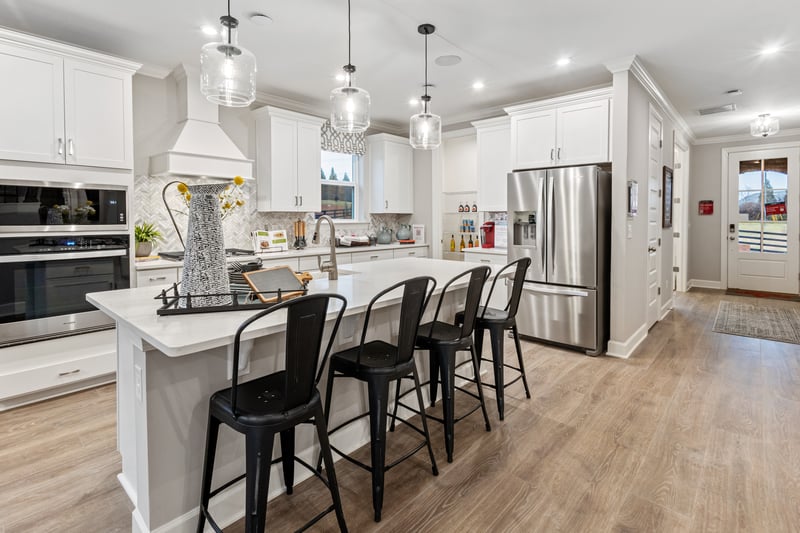 kitchen with white cabinets, white countertops, and black bar stools
