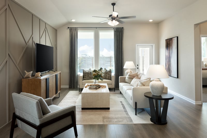 great room with brown flooring, windows & a ceiling fan