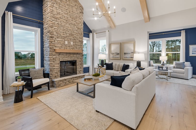 great room with wood-tone flooring, vaulted ceilings, large sectional sofa, and a stone fireplace