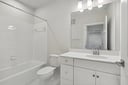 secondary bathroom with sink, shower, tub and white cabinets
