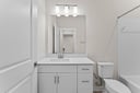secondary bedroom with white cabinets, sink, and mirror
