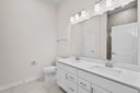 primary bathroom with white cabinets and mirror