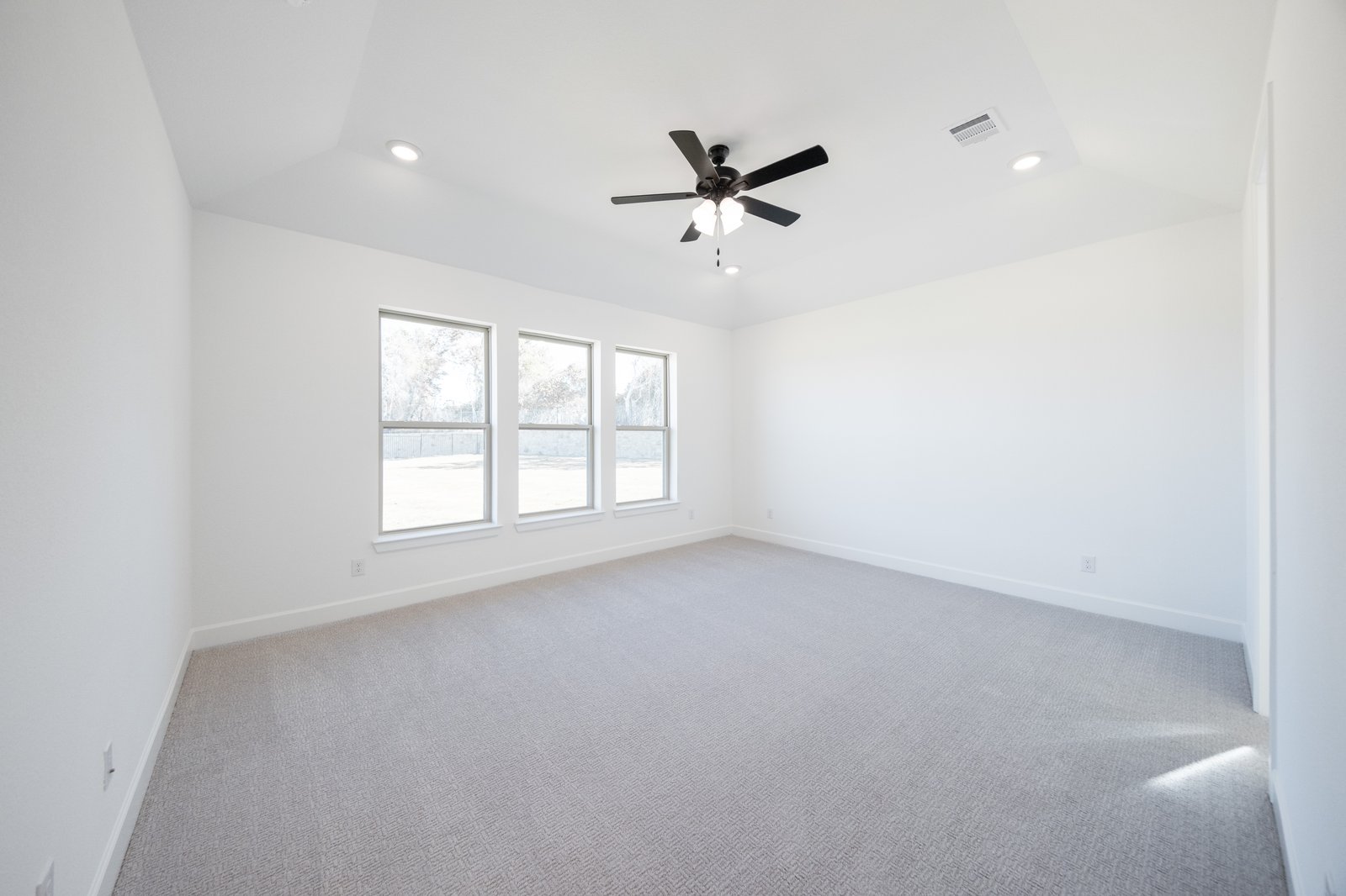 primary bedroom with large windows and carpet