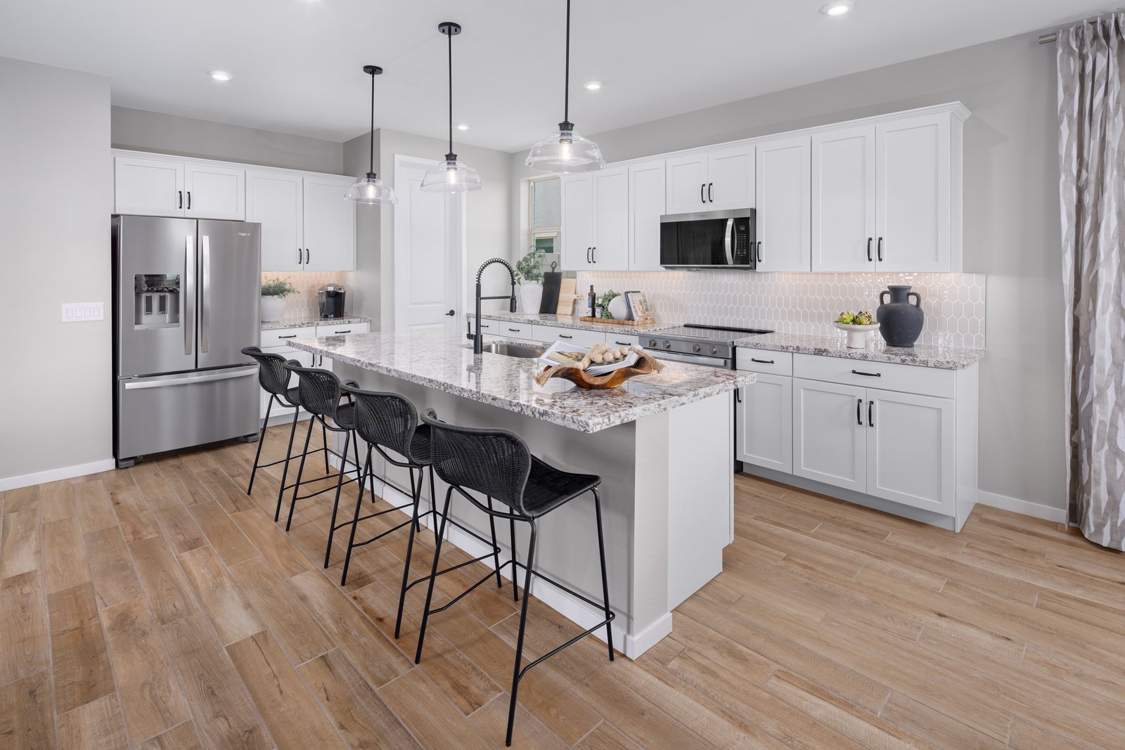 kitchen with wood-like flooring, black barstools and white cabinets