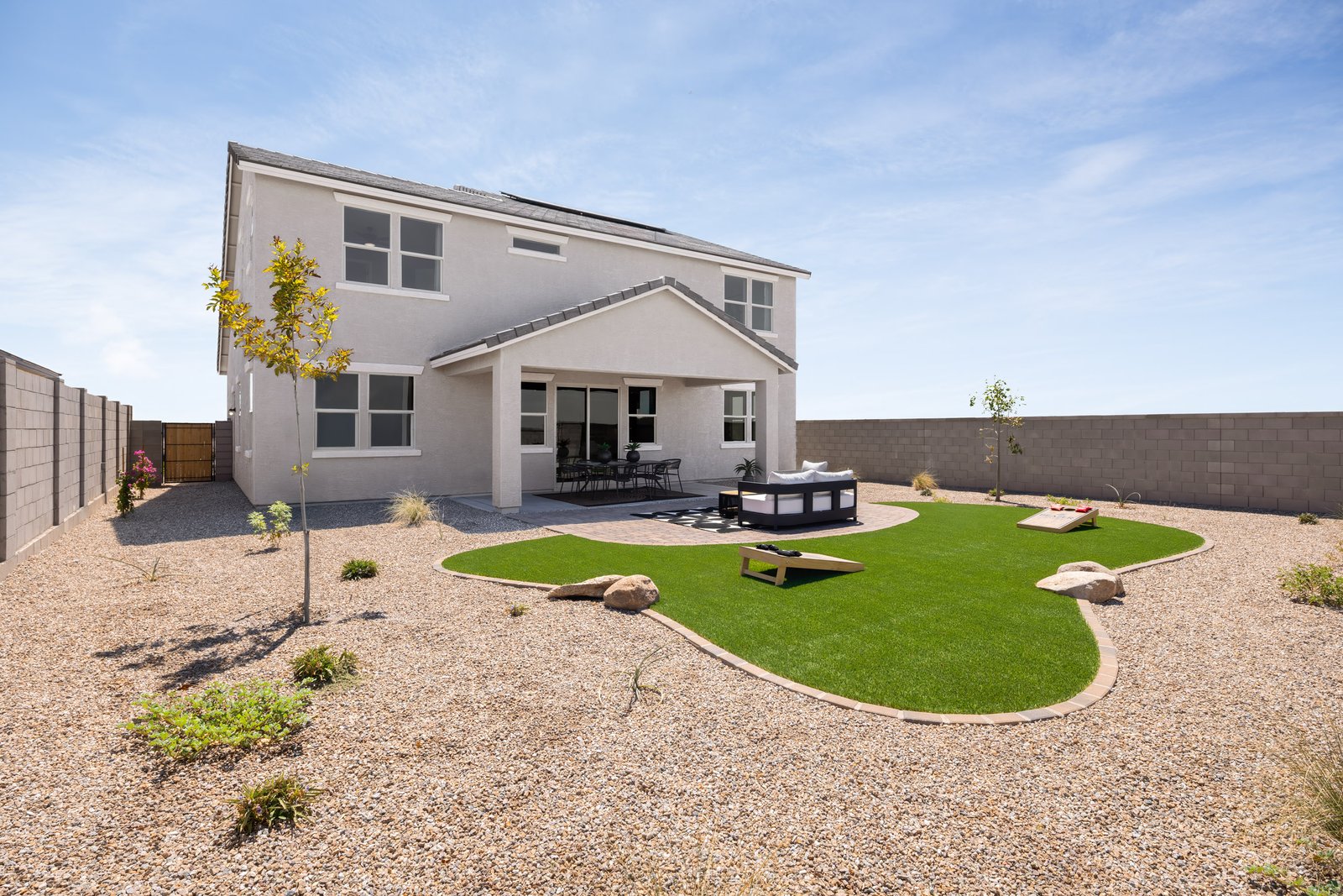 spacious landscaped backyard with artificial grass and pavers