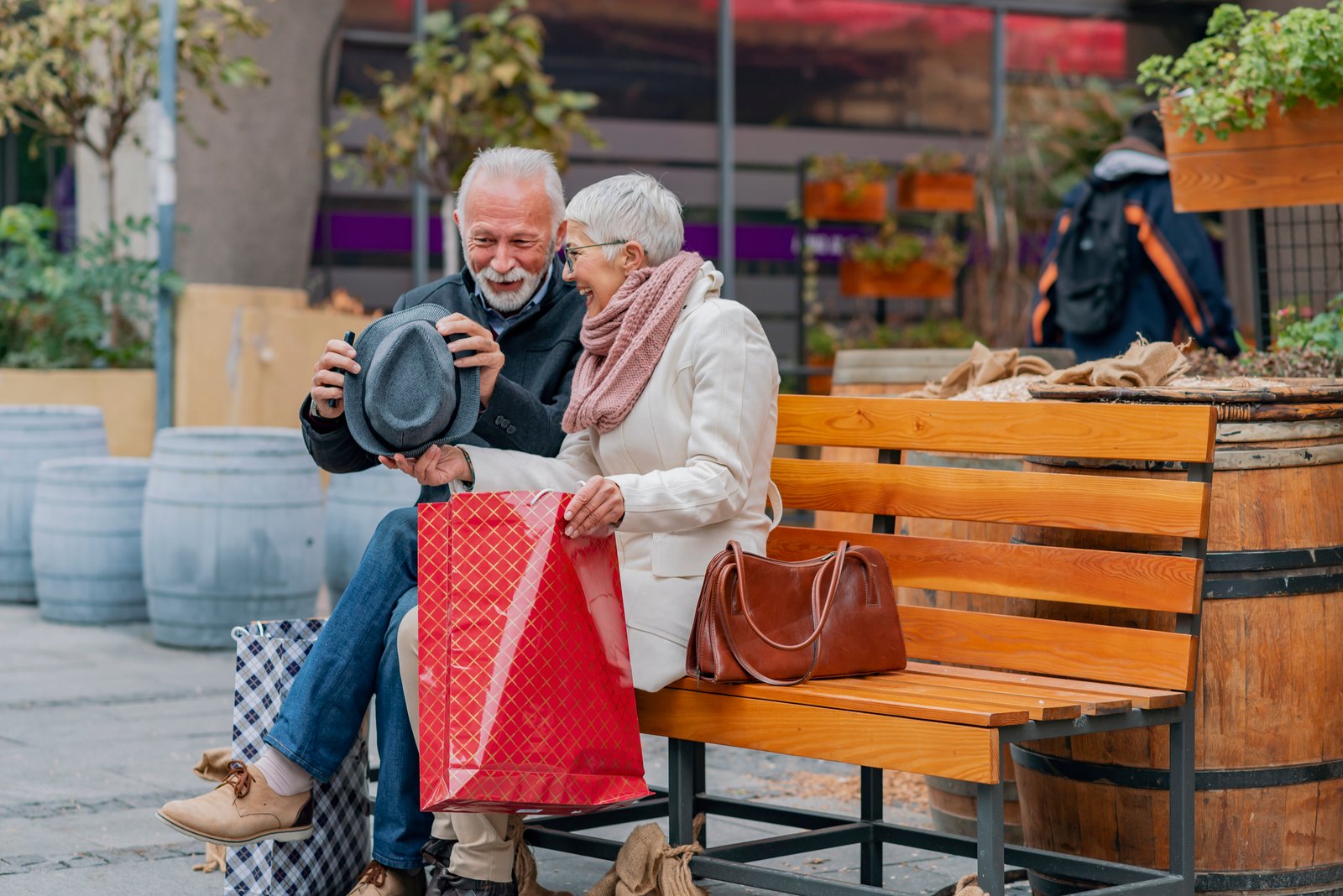 older couple on a bench laughing while looking at shopping bags.jpg