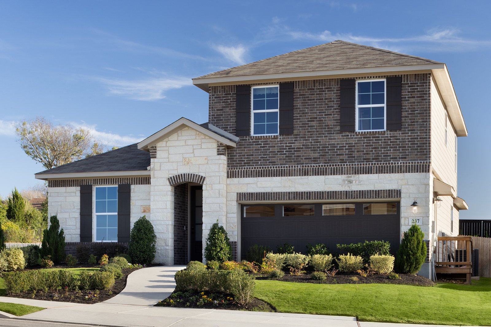 exterior with brick, grass & a 2-car garage