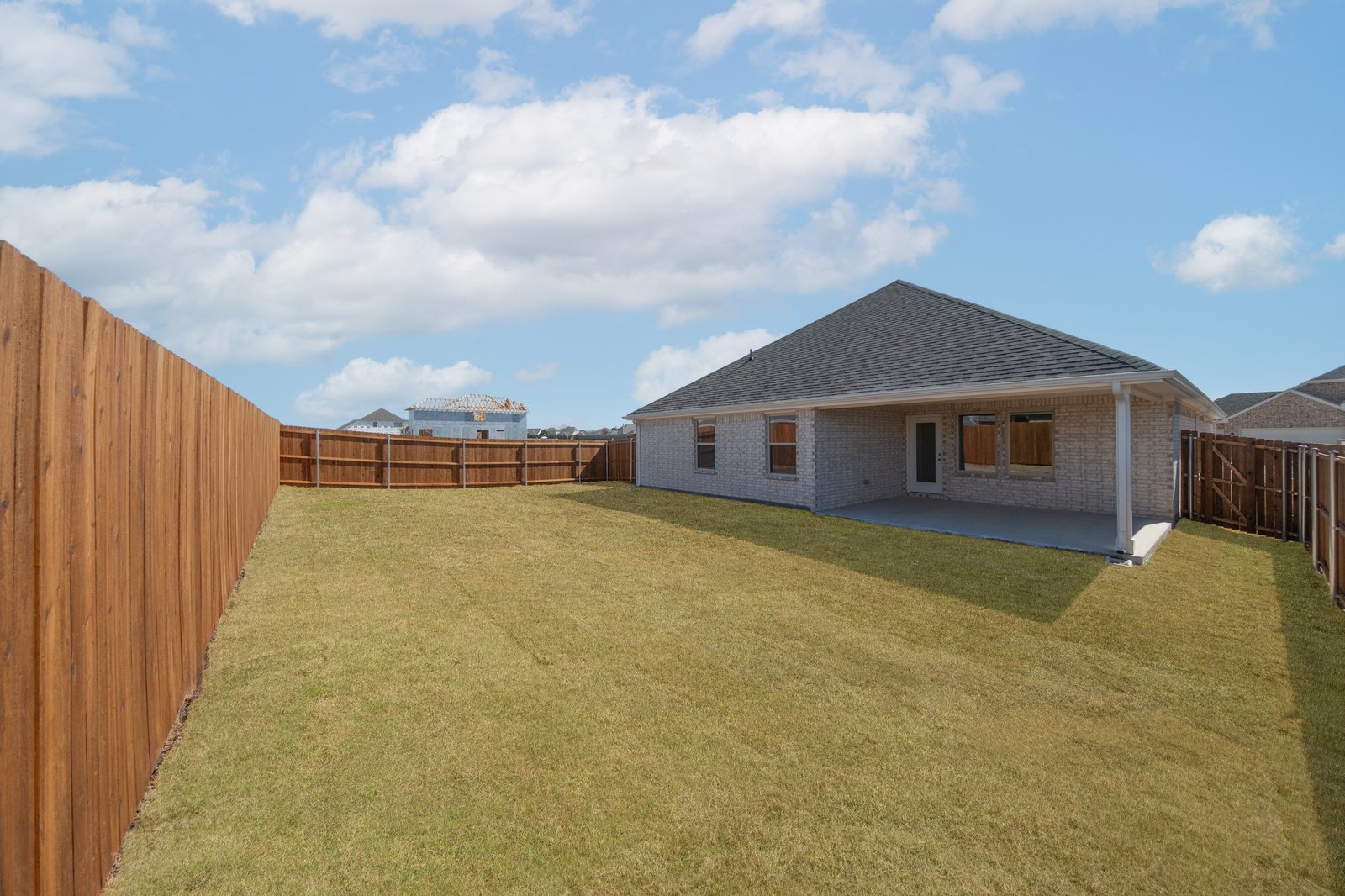 covered patio that opens up to fenced backyard