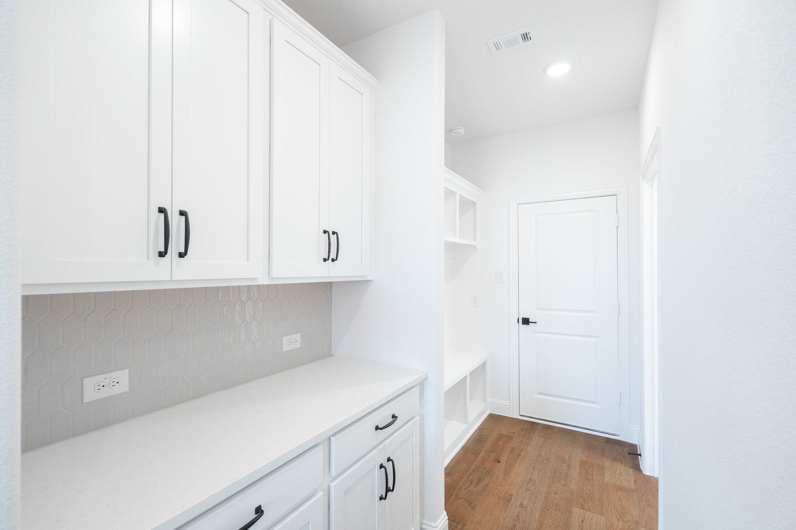 mudroom with wood floors and white shelves with bench