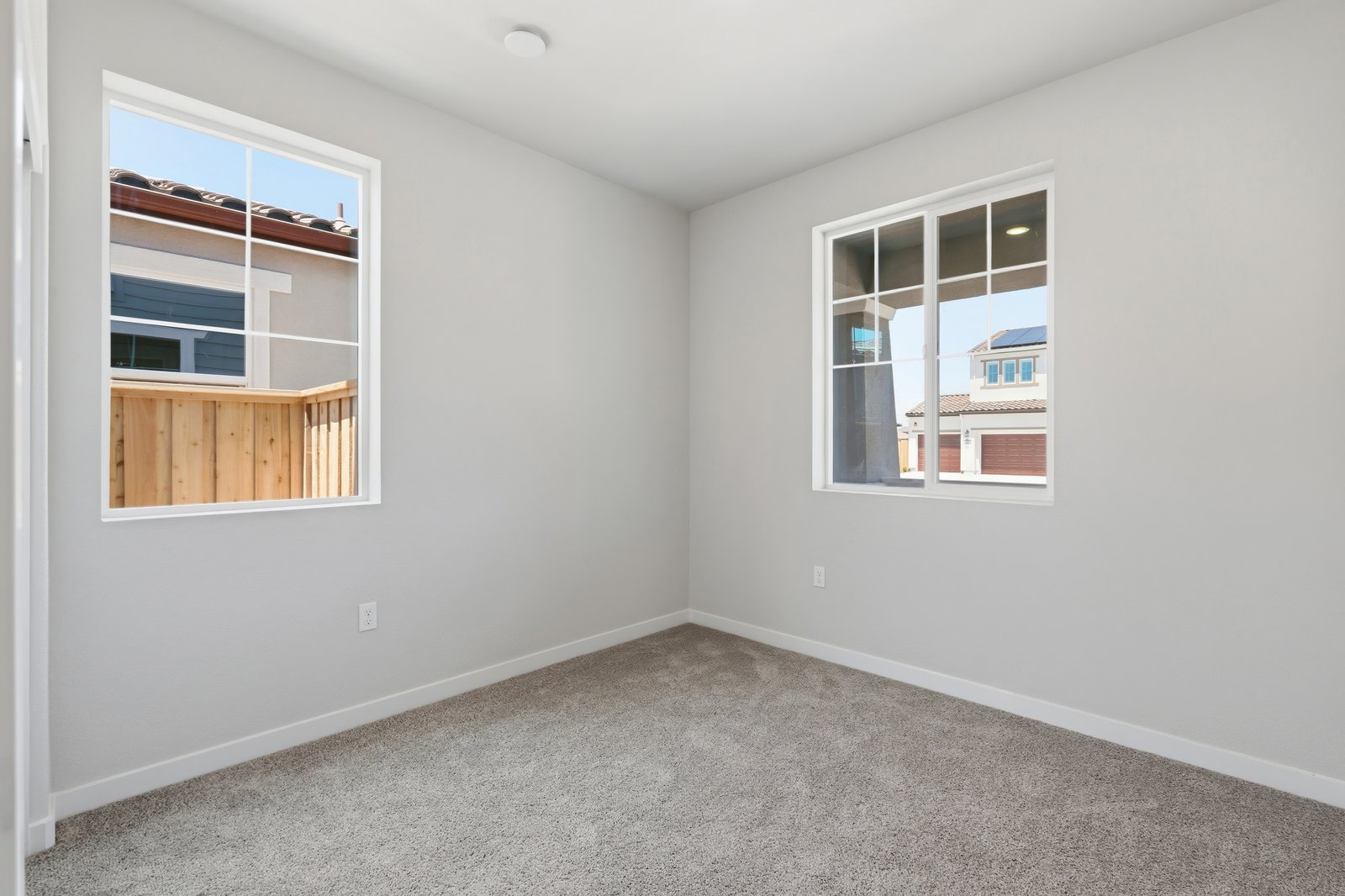 bedroom with tan carpet, light gray walls, and two windows