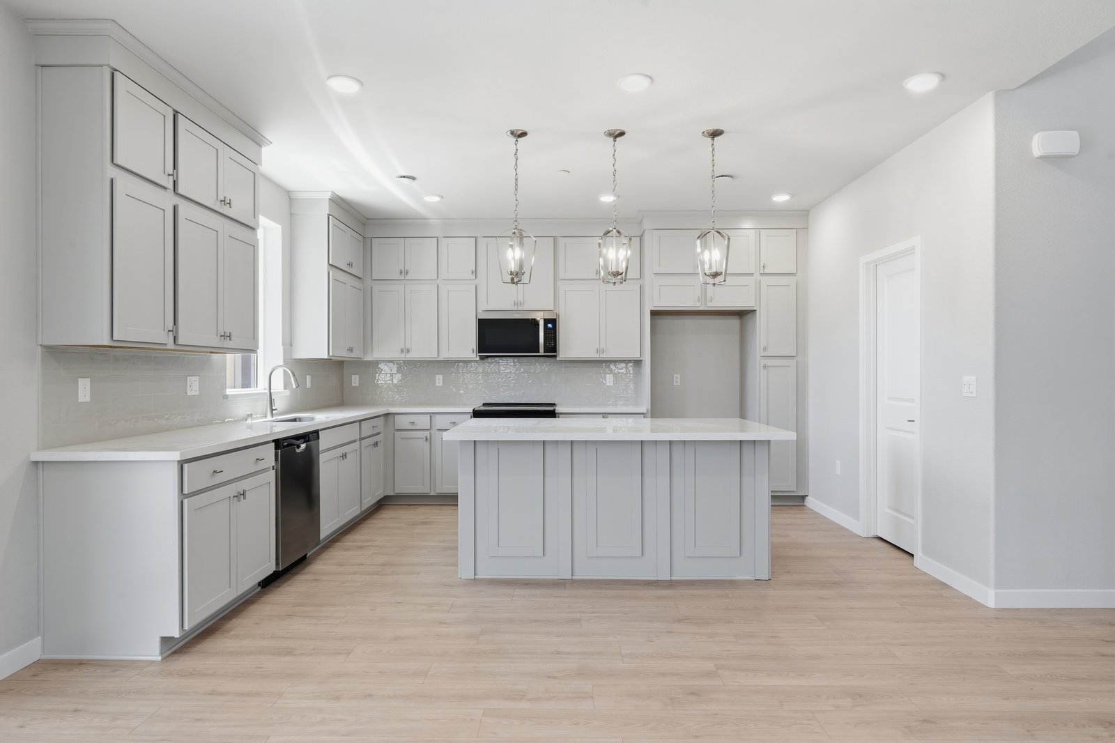 kitchen with light wood floors, light gray ceiling height cabinets, white quartz counters, and window above sink