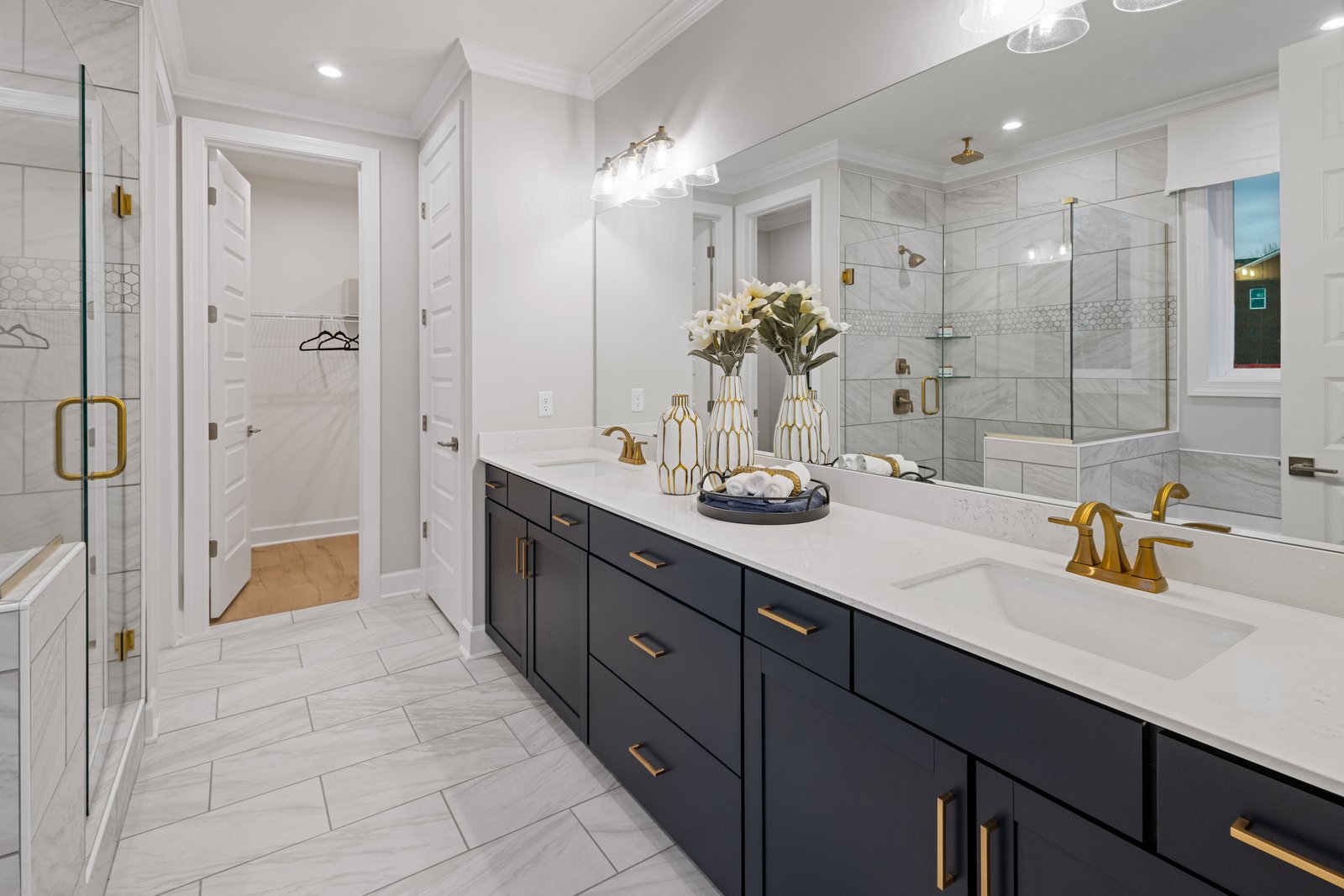 primary bathroom with double sink vanity, blue cabinets, white countertops, and gold accents