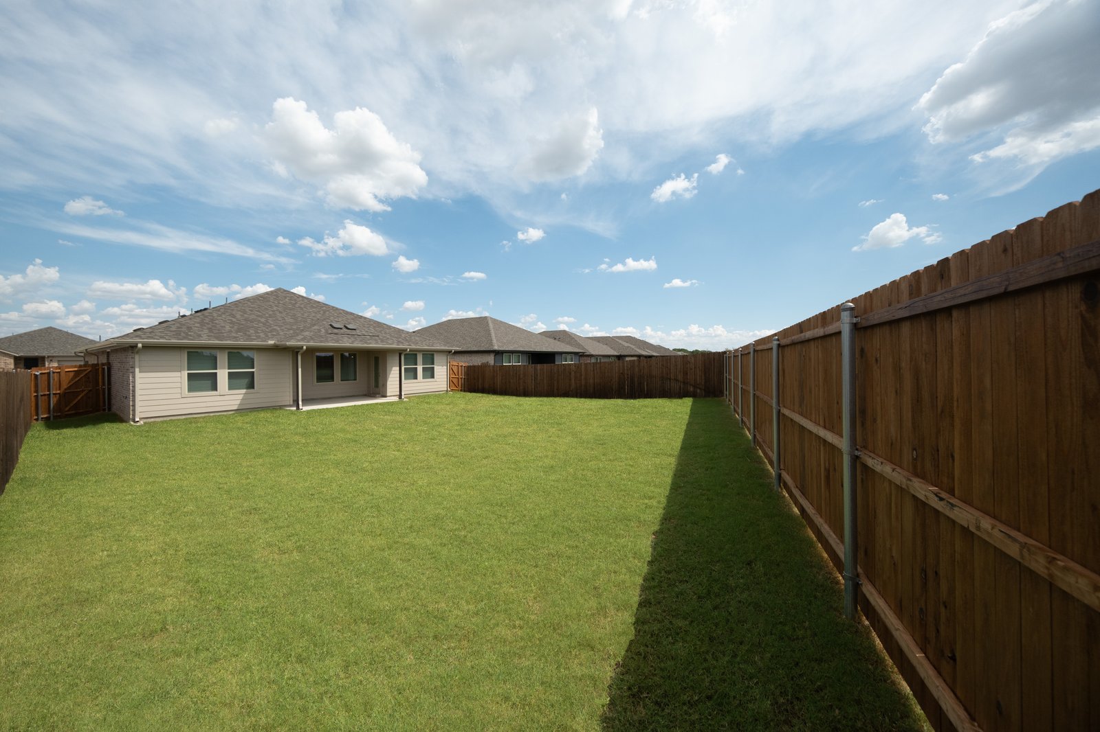 covered patio that opens up to large fenced backyard