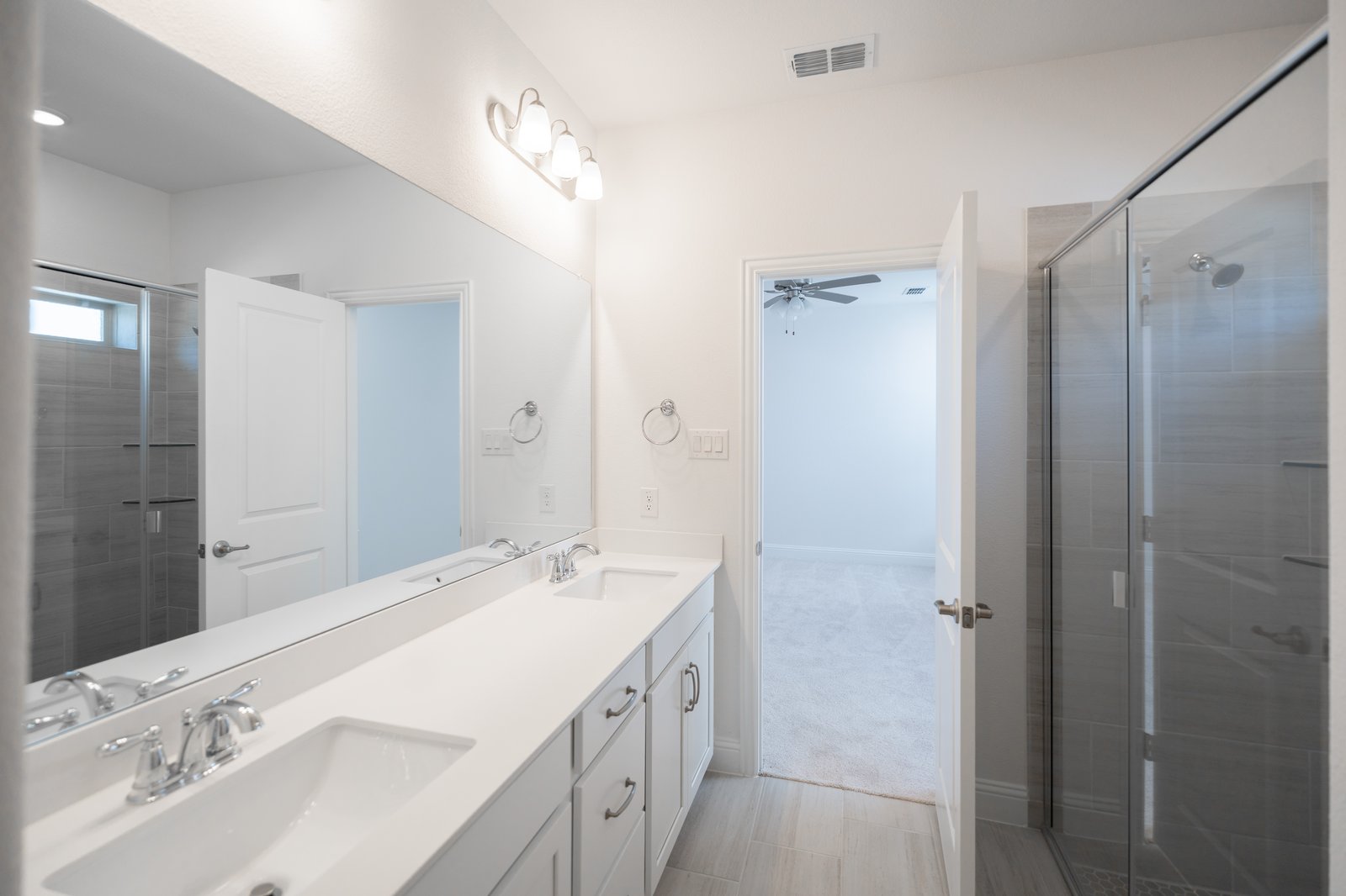 primary bathroom with walk-in shower and white cabinets