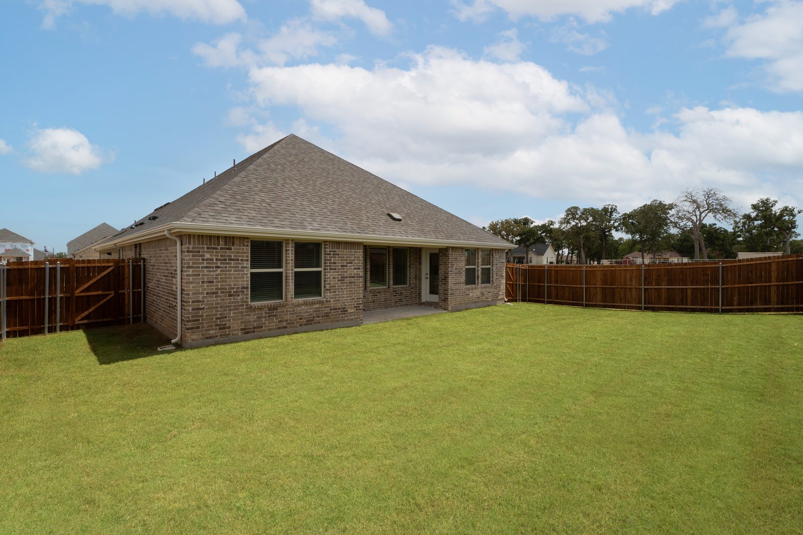 large fenced backyard with covered patio