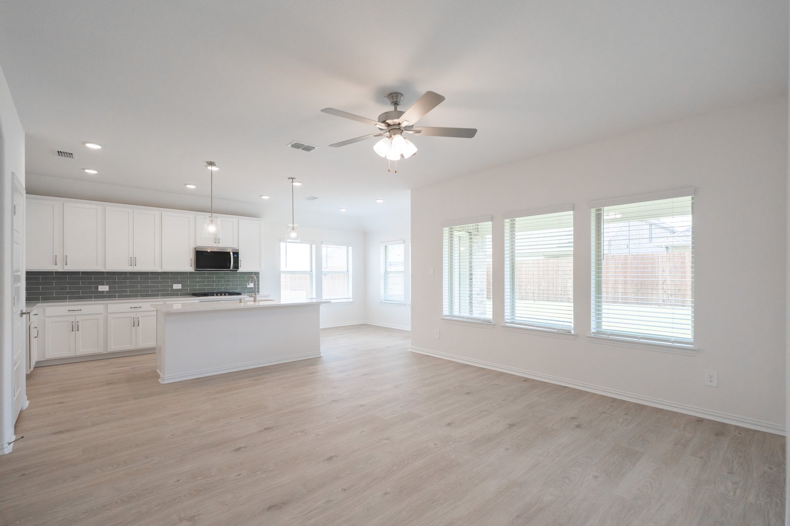 great room with large windows with blinds and ceiling fan