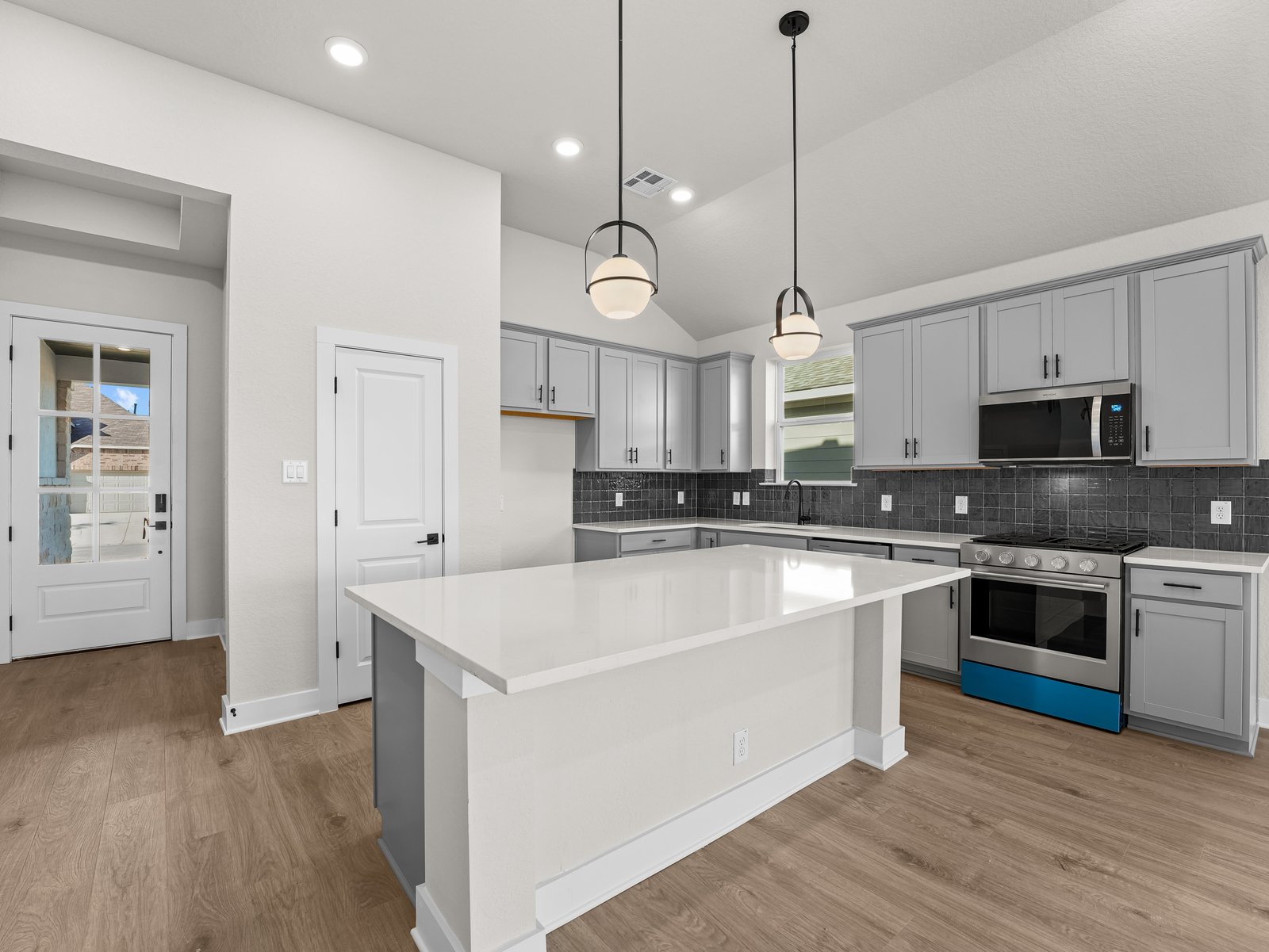 kitchen with quartz countertops, brown flooring and pendant lighting