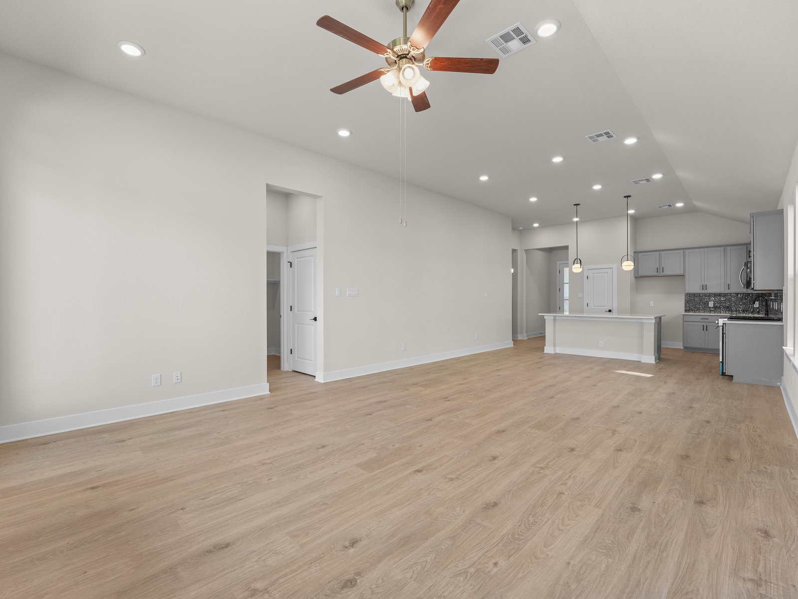 great room with brown flooring, windows and a ceiling fan