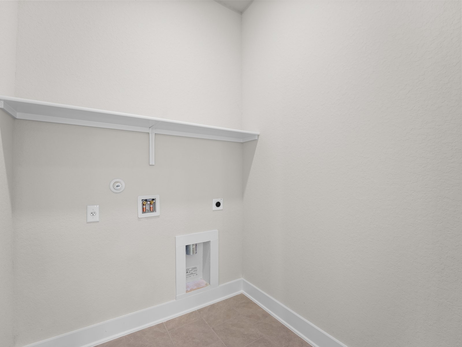 laundry room with brown flooring and shelving