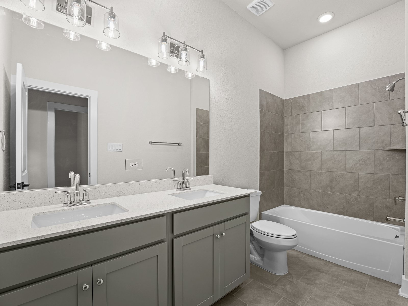 secondary bathroom with brown flooring, dual sinks and a soaking tub