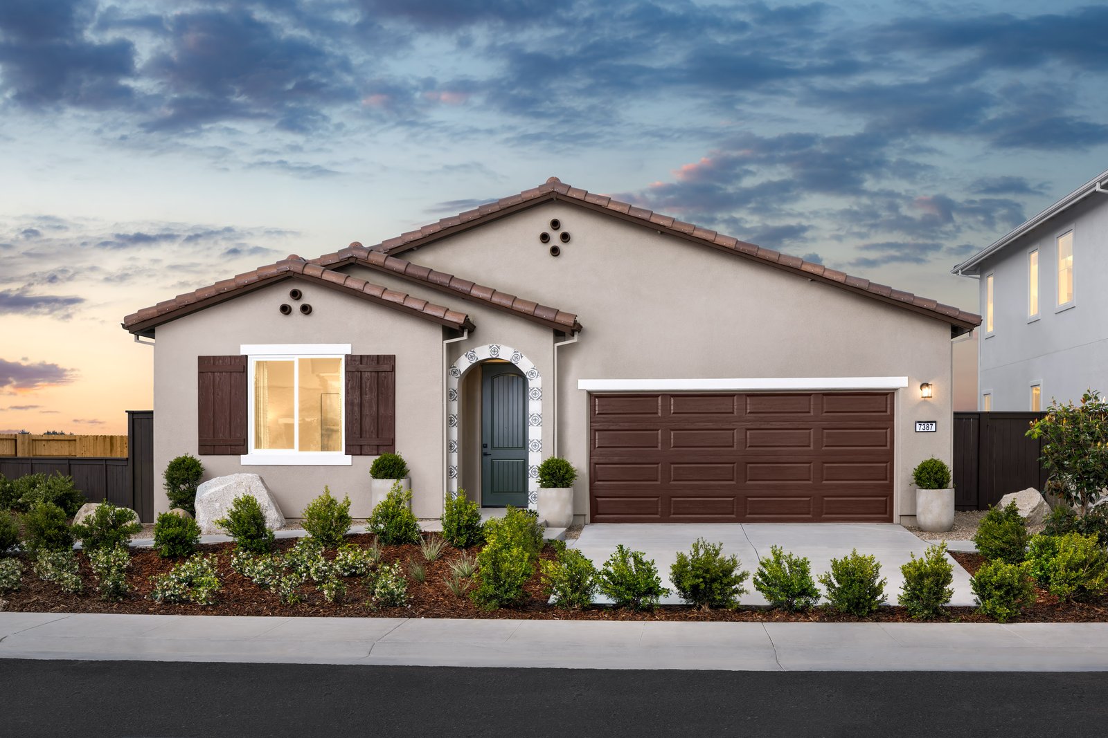 front exterior of brown single-story spanish style home at dusk