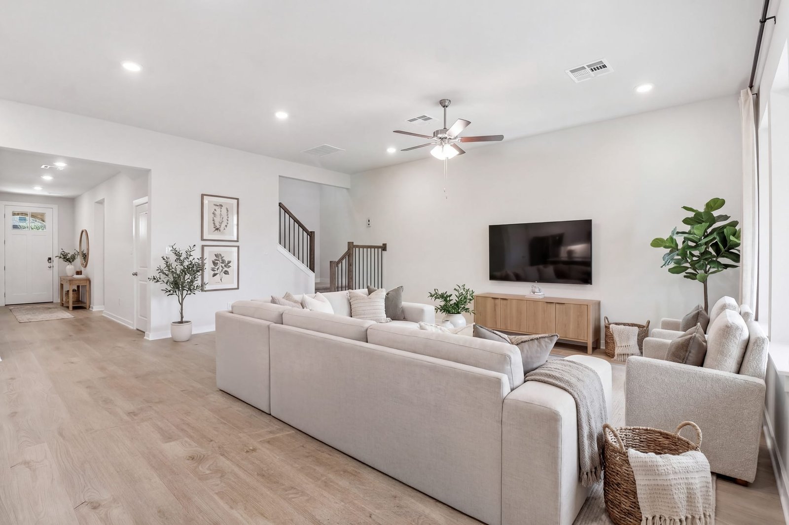great room with brown flooring, windows and a ceiling fan