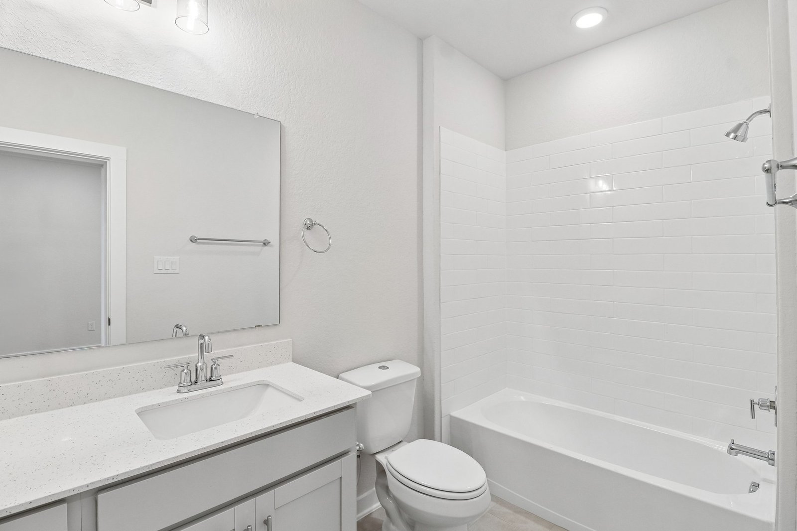 secondary bathroom with white flooring, a sink and a soaking tub