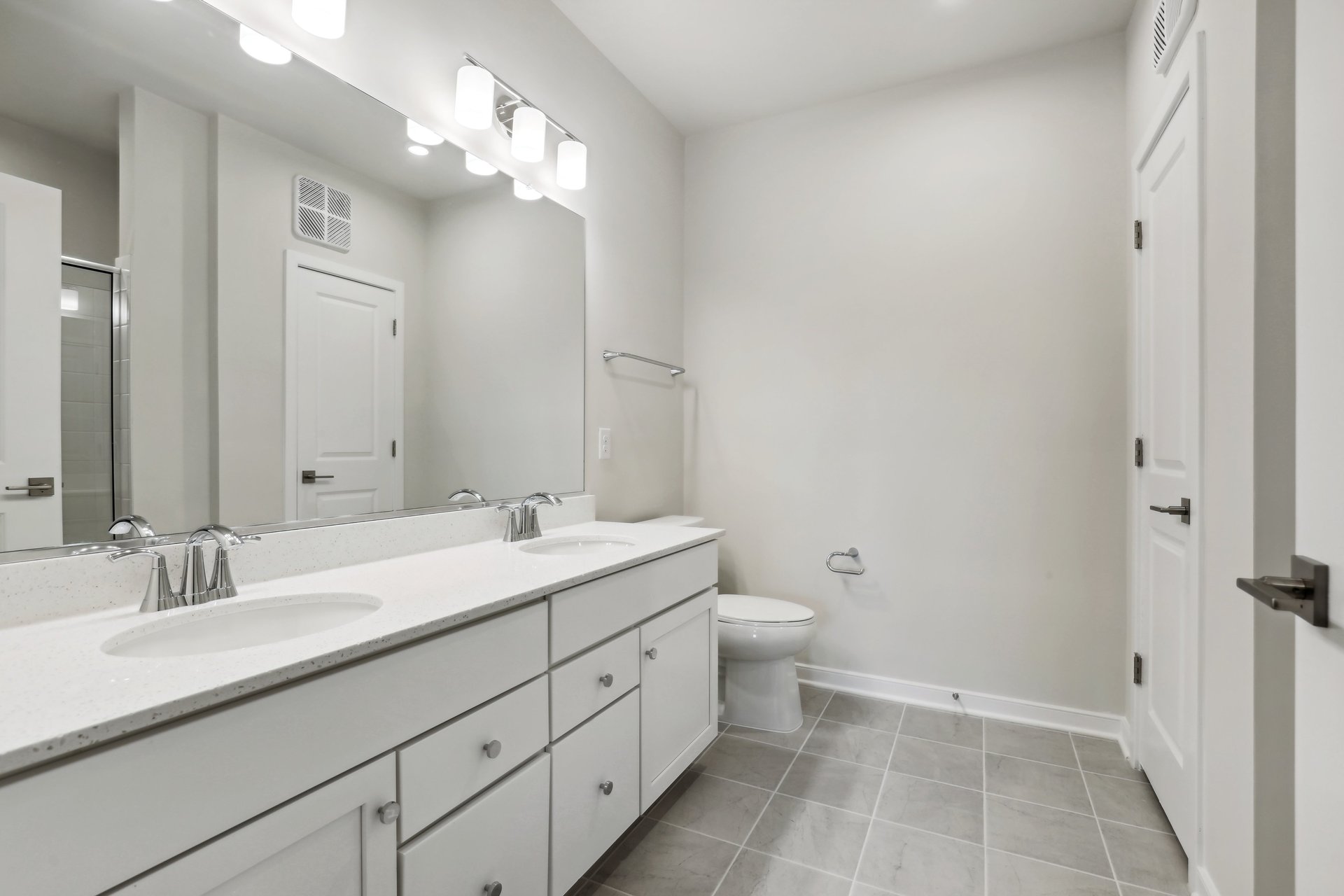 primary bathroom with two sinks and white cabinets