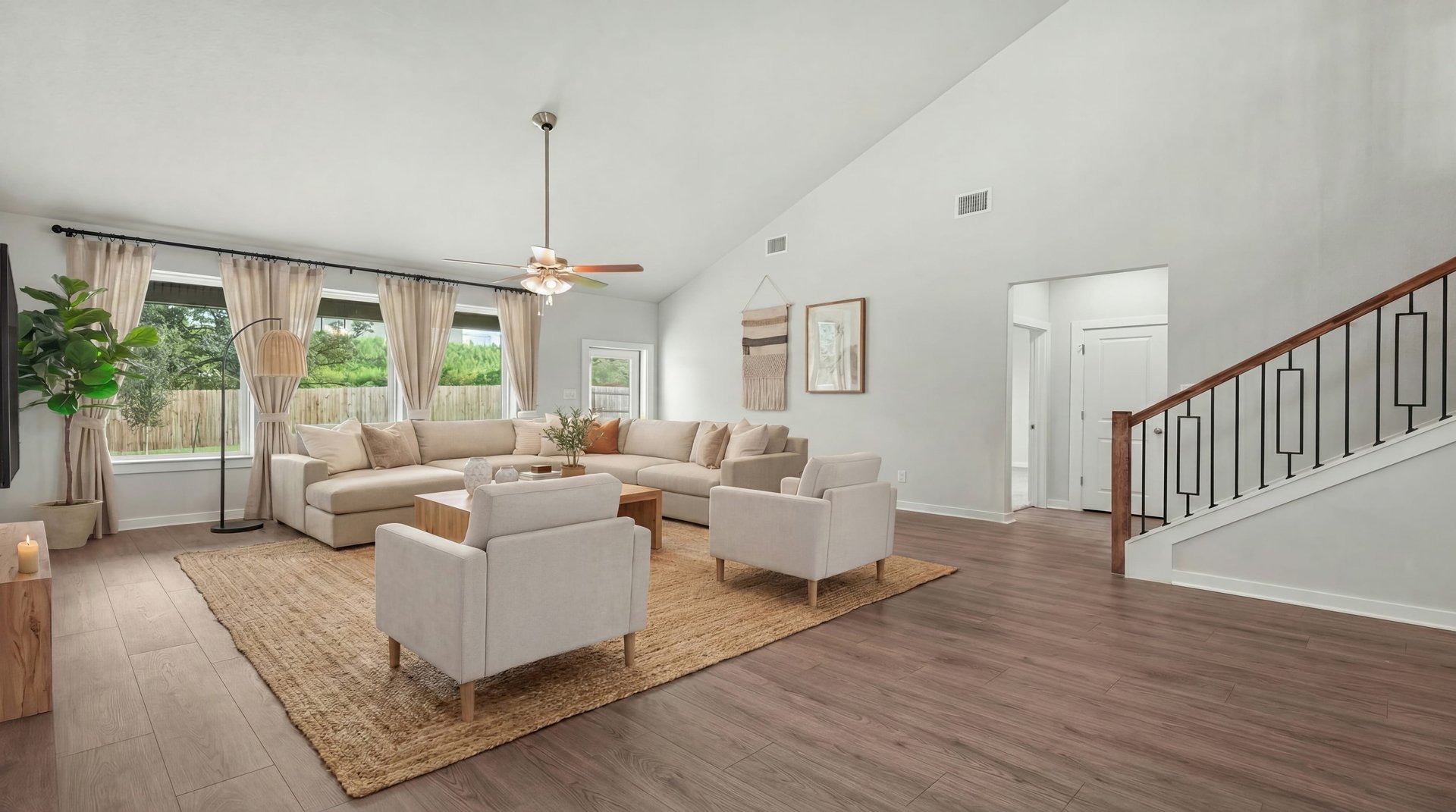 Great room with brown floor, a ceiling fan and windows