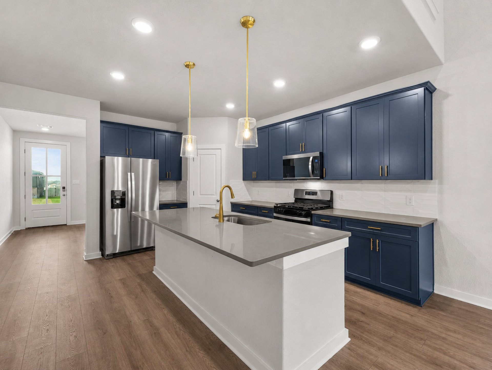 Kitchen with brown flooring, navy blue cabinents and quartz countertop