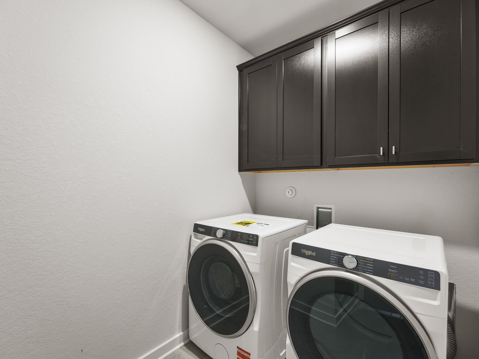 laundry room with brown cabinets and gray flooring