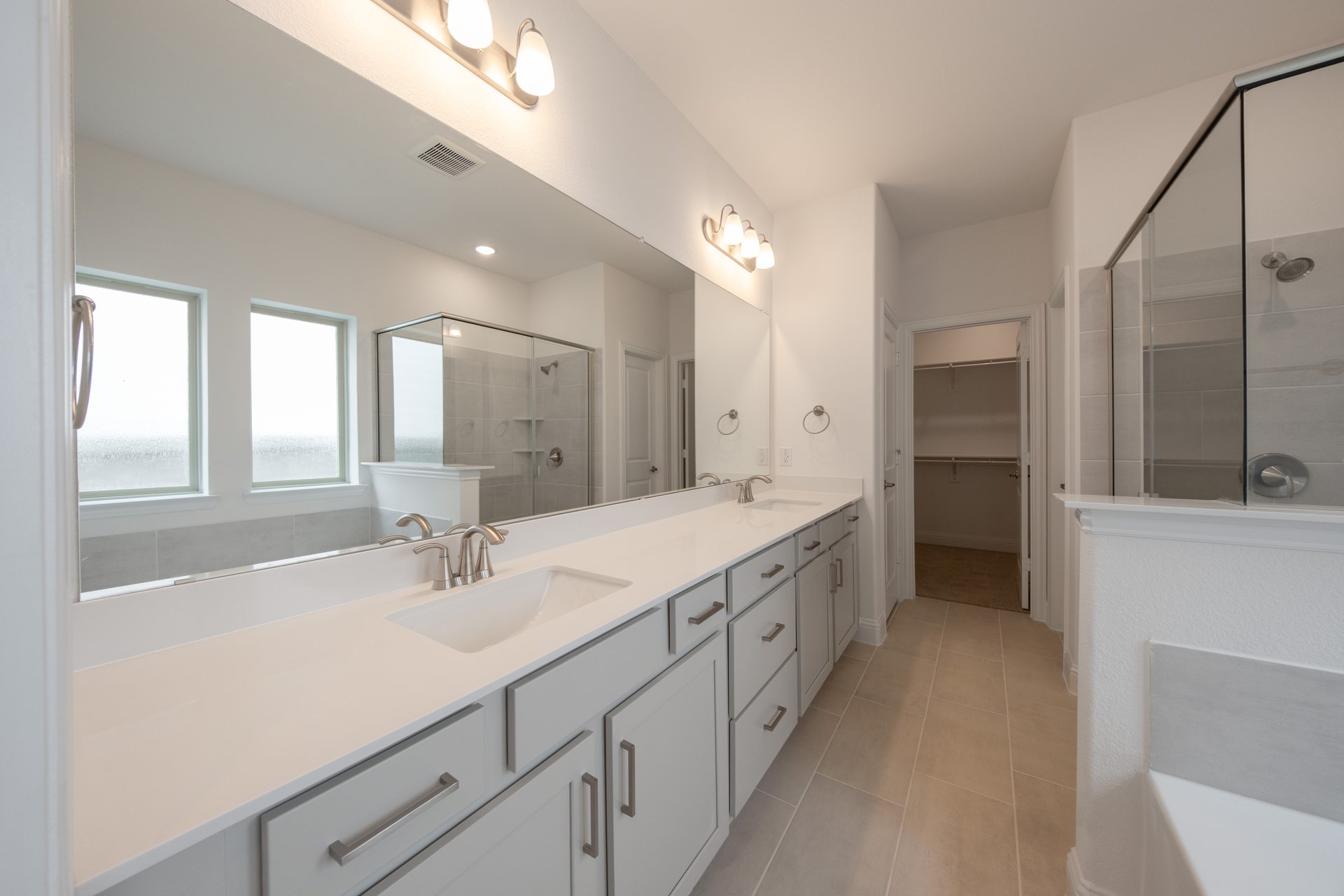 primary bathroom with tile flooring and double sinks