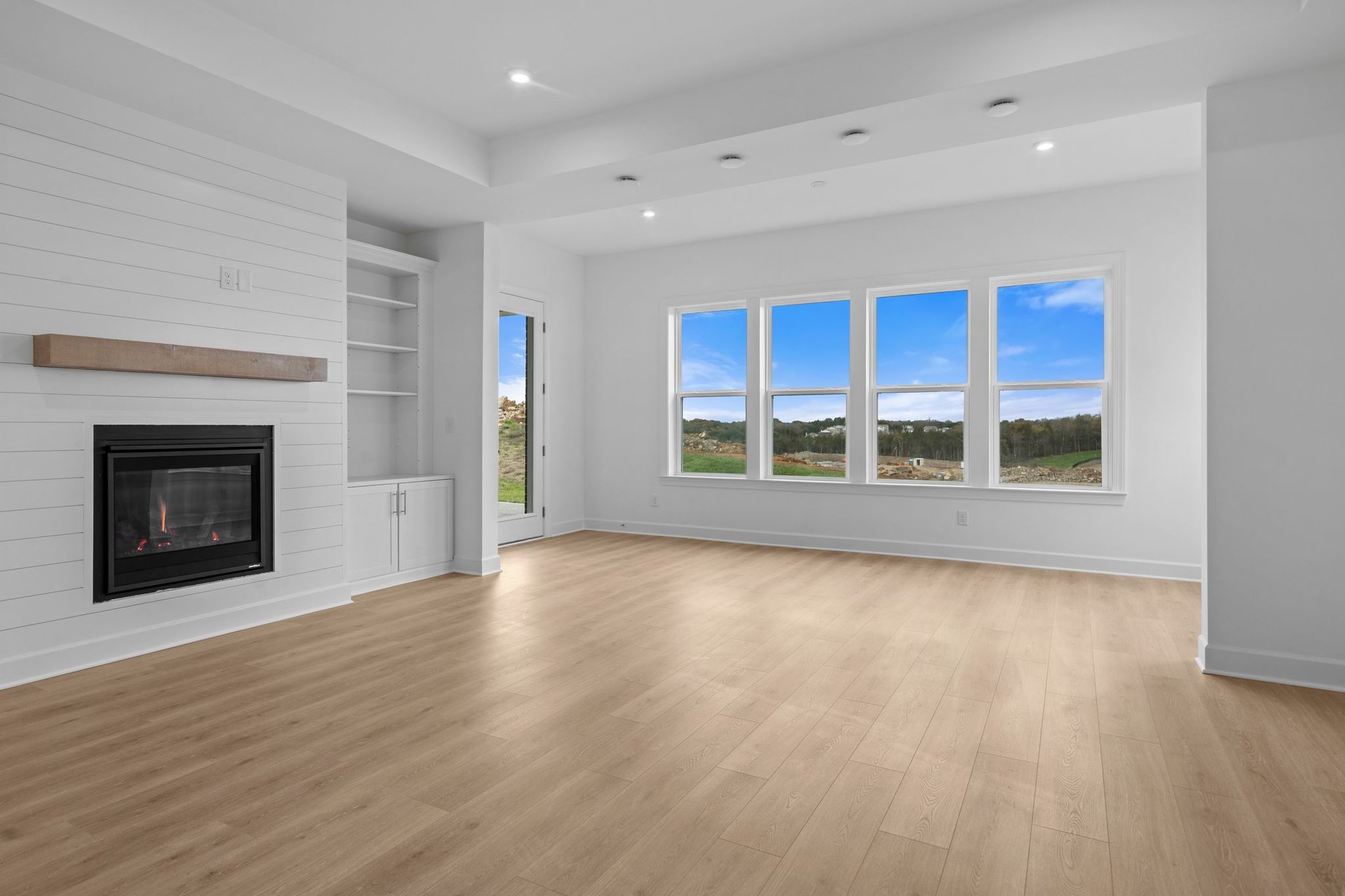 great room with wood floors, white shiplap fireplace, and morning room