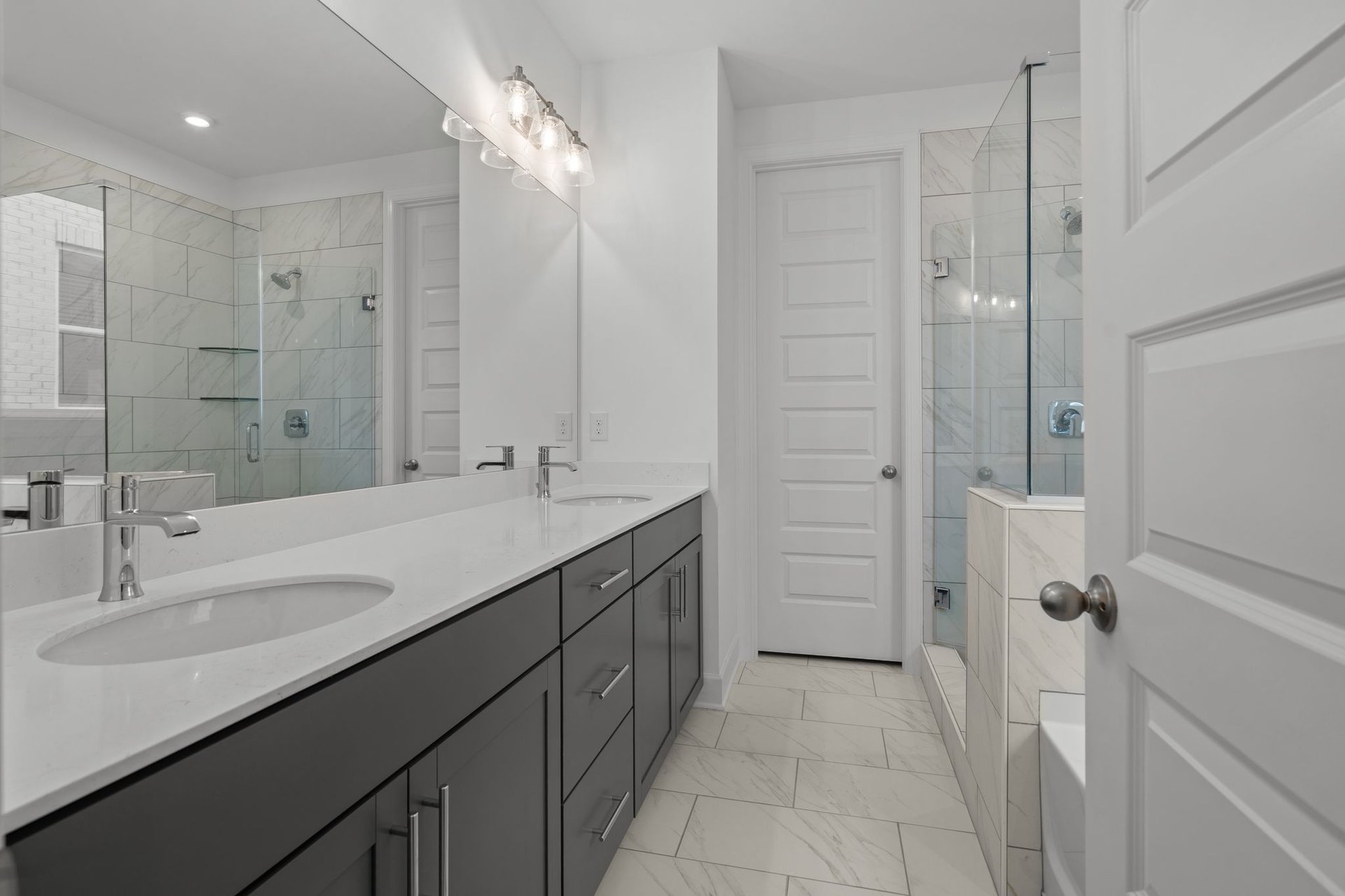 primary bathroom with gray cabinets, white countertops, and a glass shower