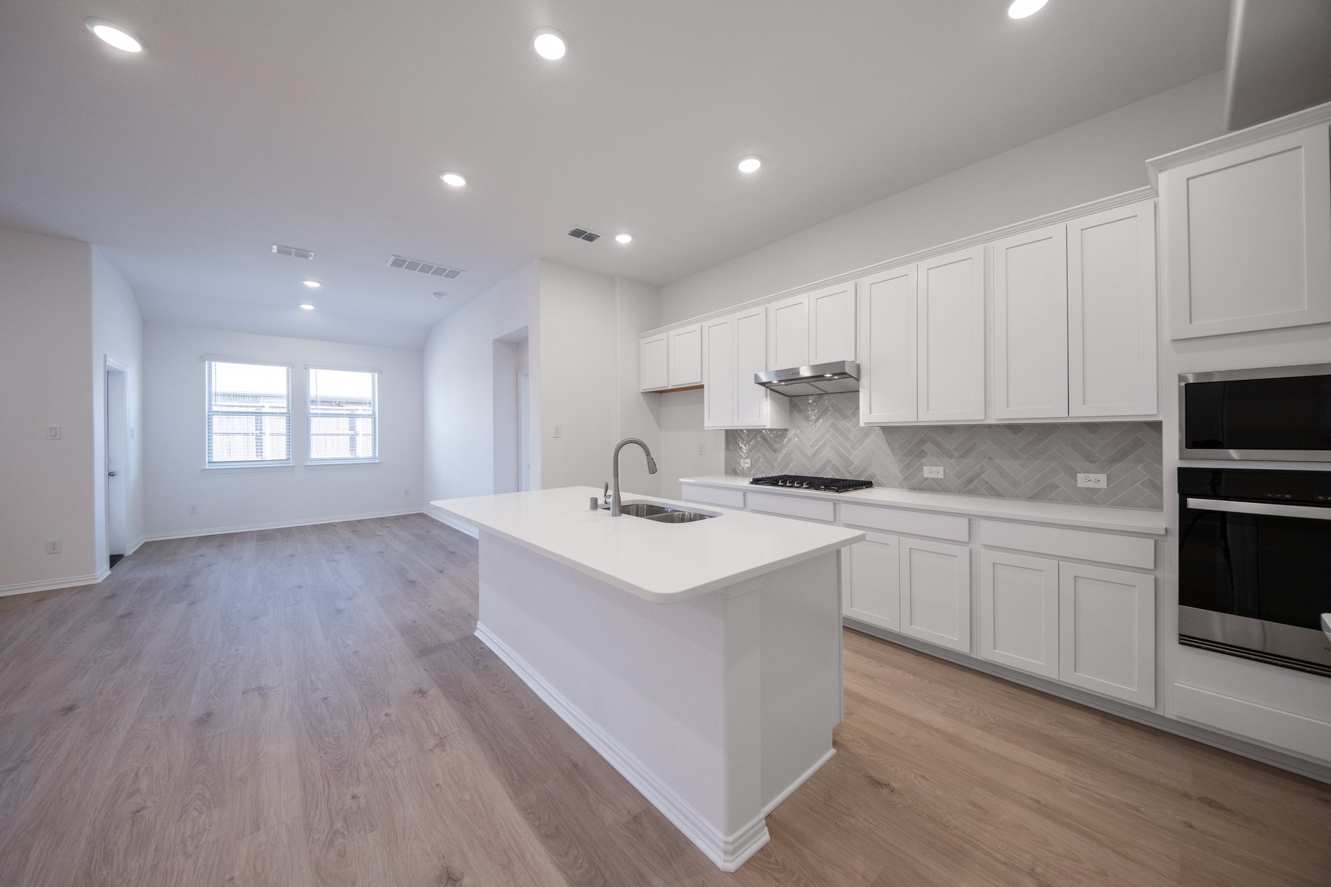 open kitchen with wood floors and white cabinets