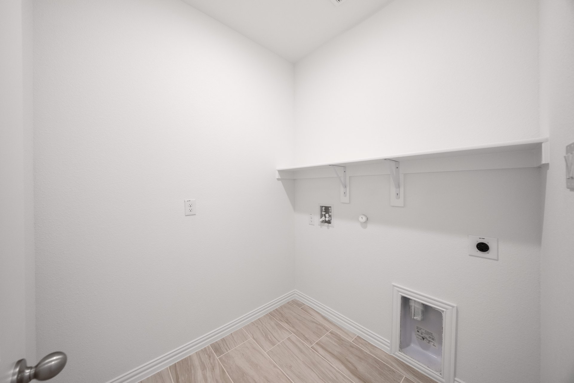 laundry room with tile floors and white shelf
