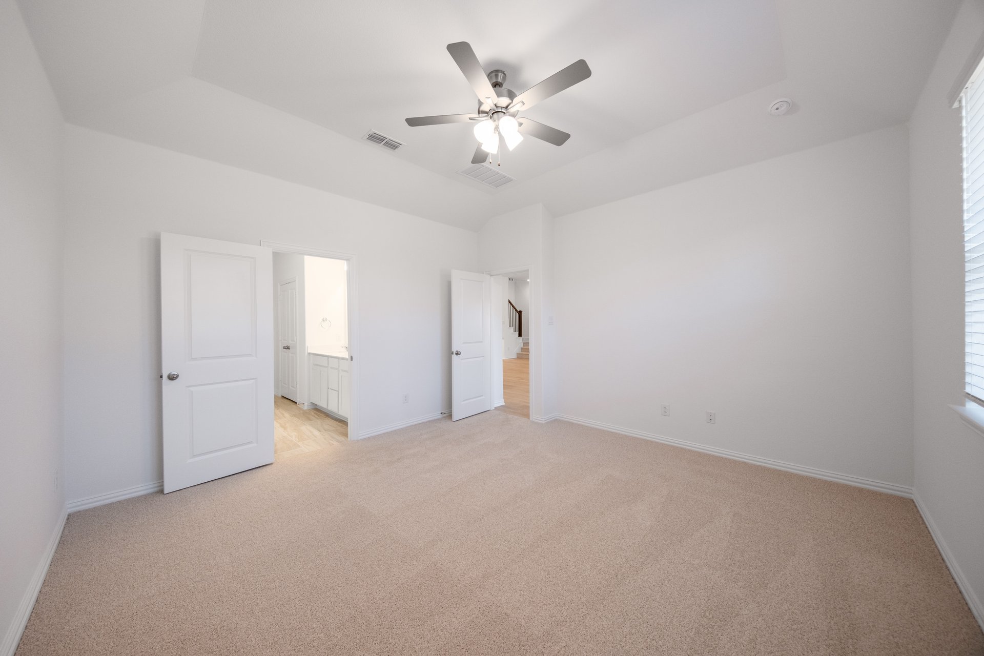 primary bedroom with carpet and ceiling fan