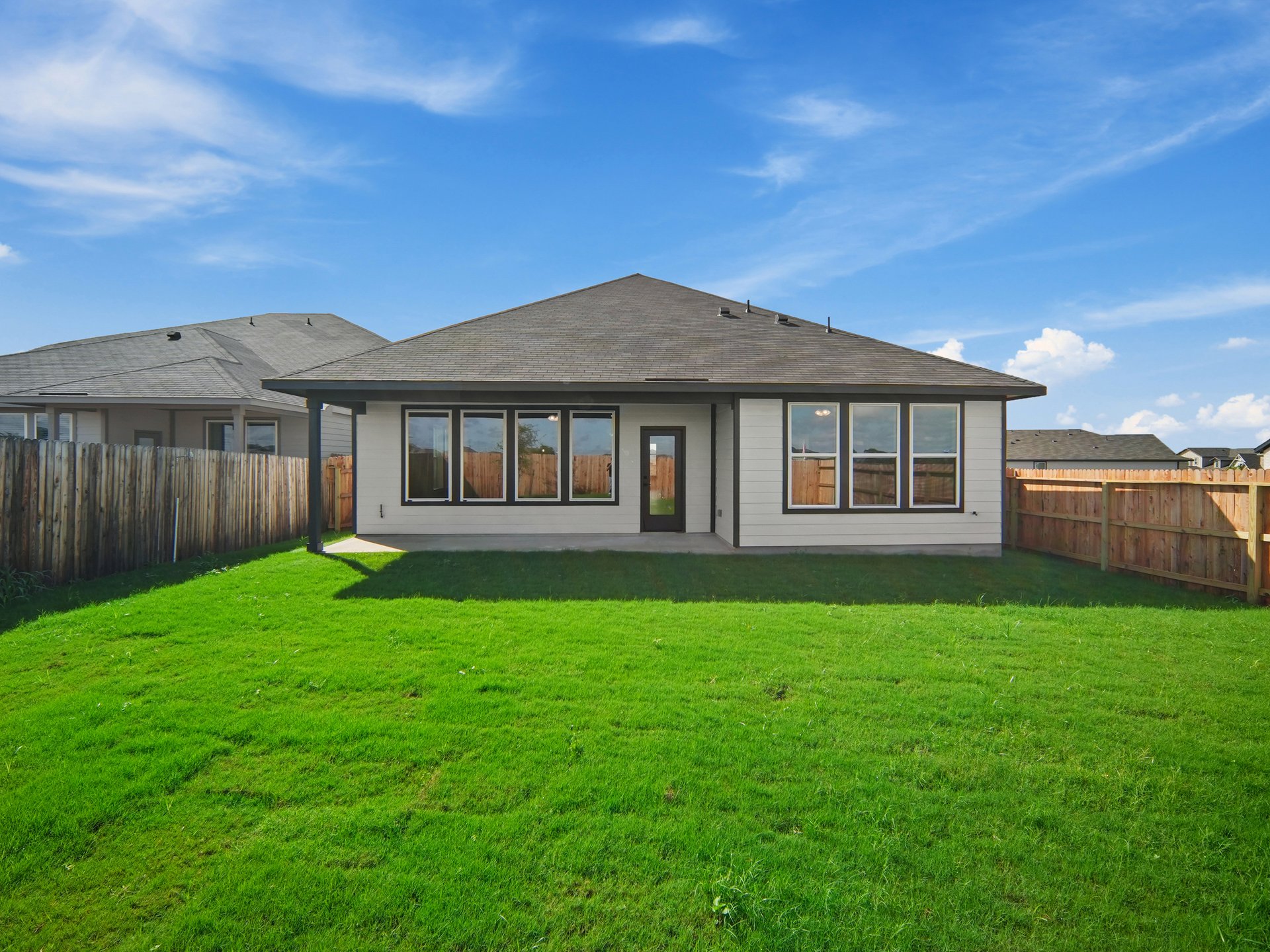 backyard with landscaped grass and brown fence