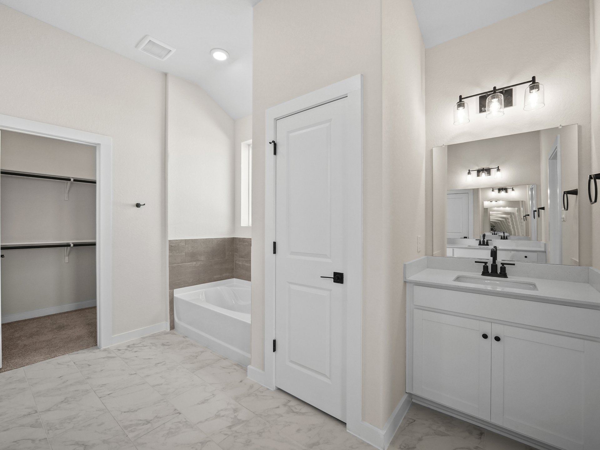 primary bath with white flooring, a sink and a soaking tub