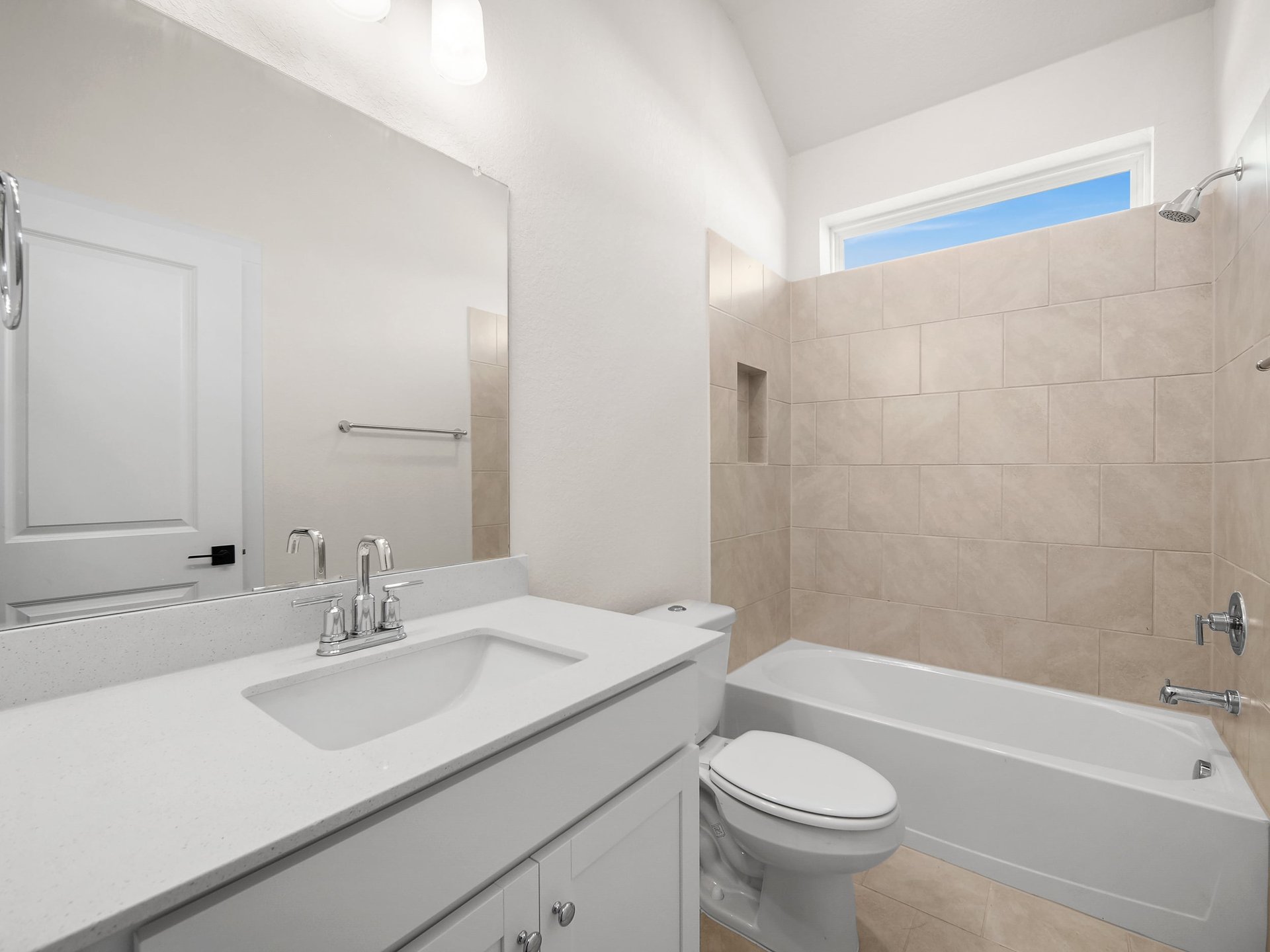 secondary bathroom with sink, soaking tub and brown tile
