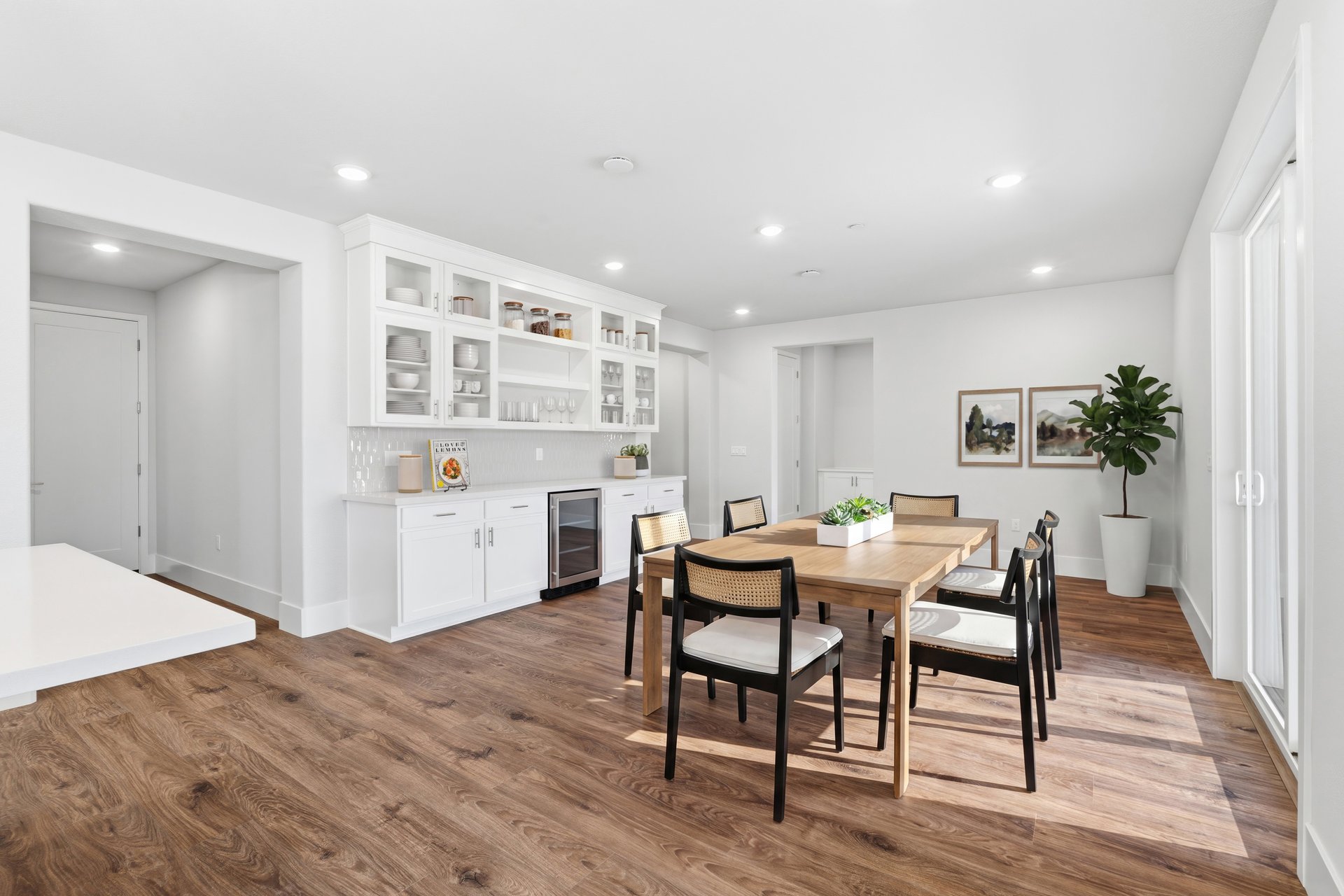 dining room with wood floors, wood table with six black chairs, and large white built-in beverage bar with drink refrigerator