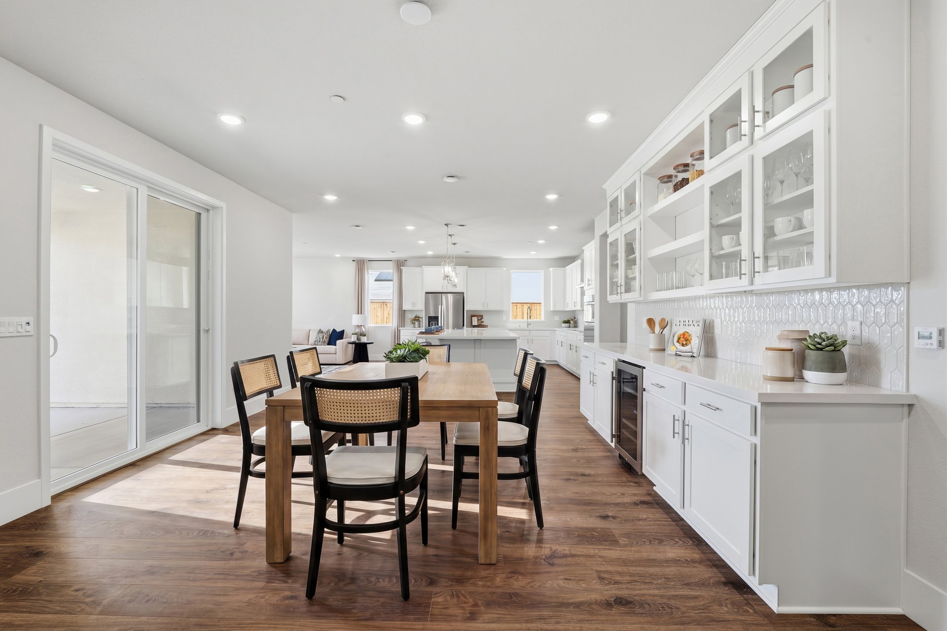 dining room with wood floors, built-in white cabinetry with drink refrigerator, and sliding glass door to the back patio