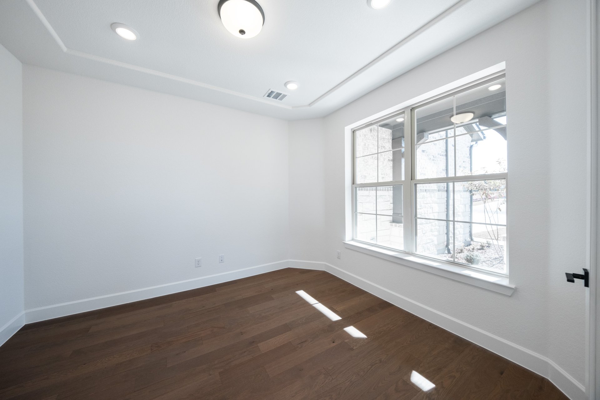 study with large window and wood flooring