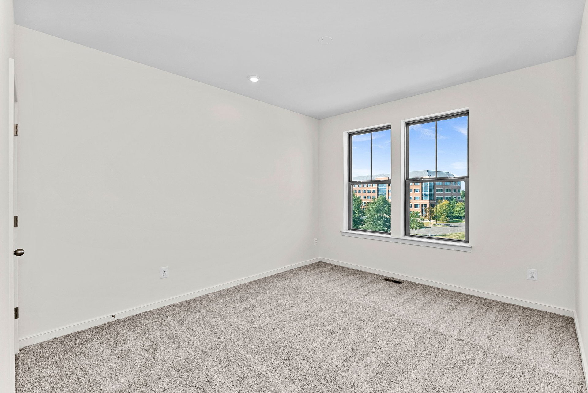 secondary bedroom with two windows and carpet