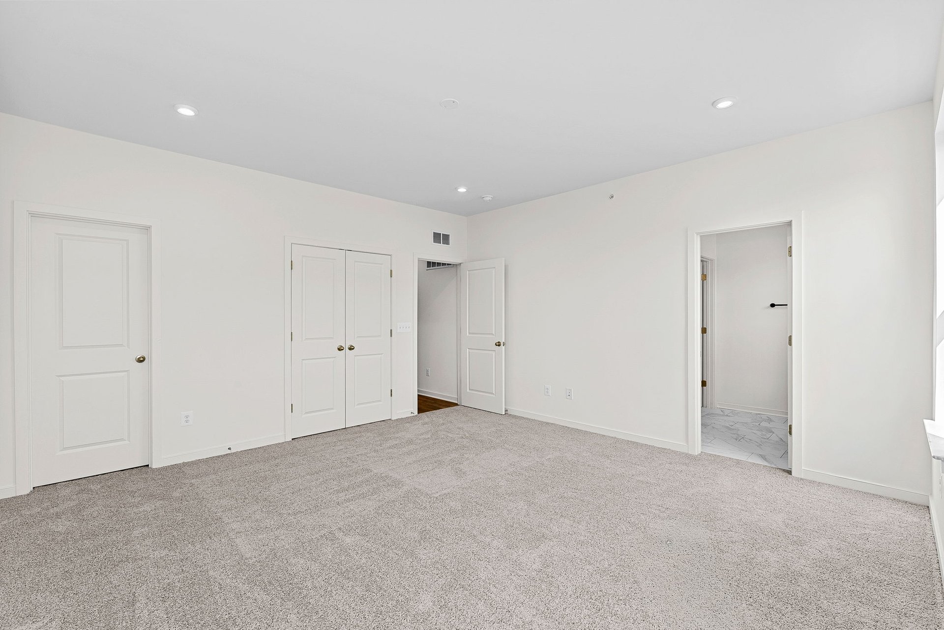 Primary bedroom with doors to walk-in closet, hallway, and primary bathroom