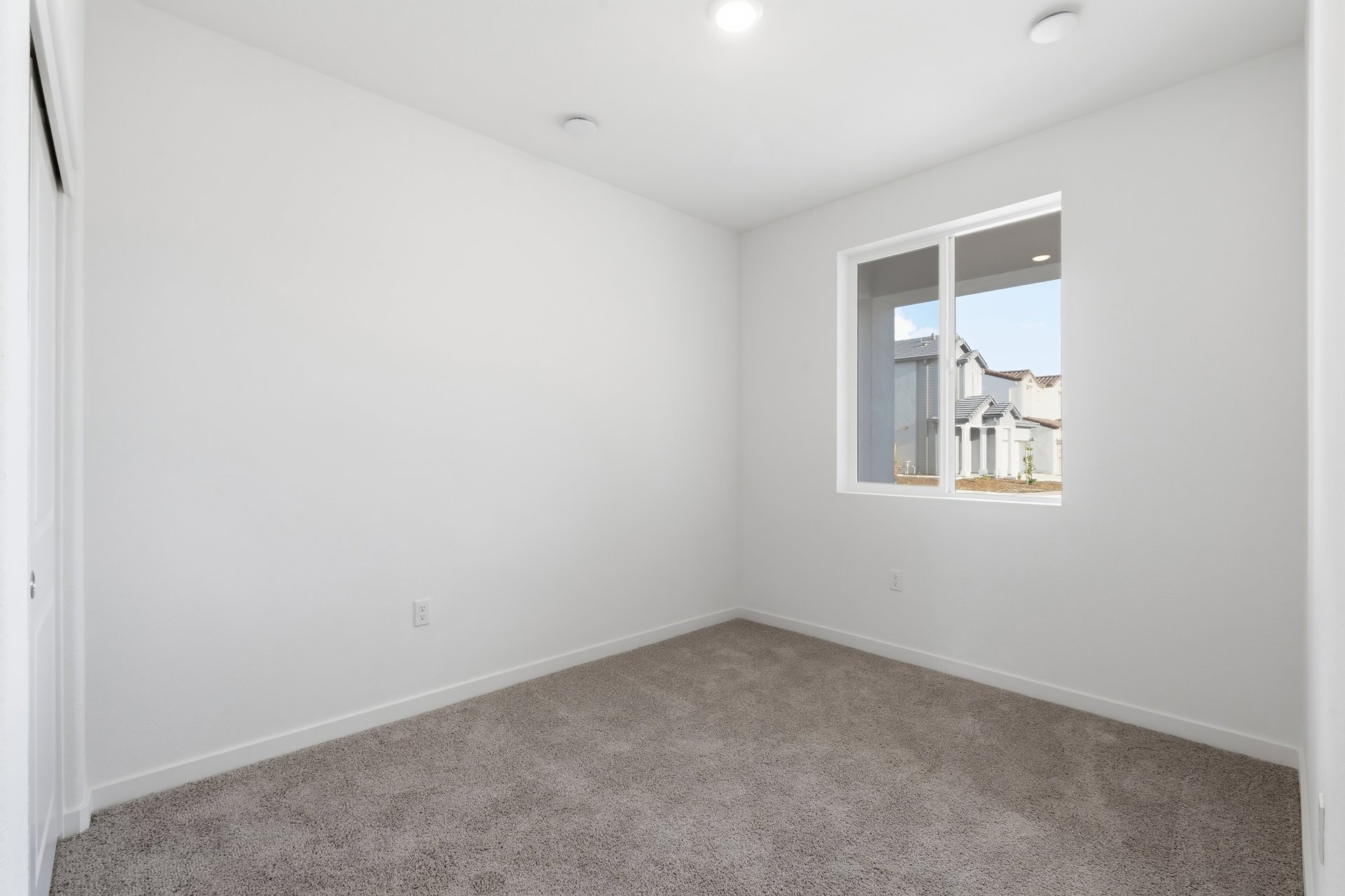 bedroom with tan carpet, white walls, and window