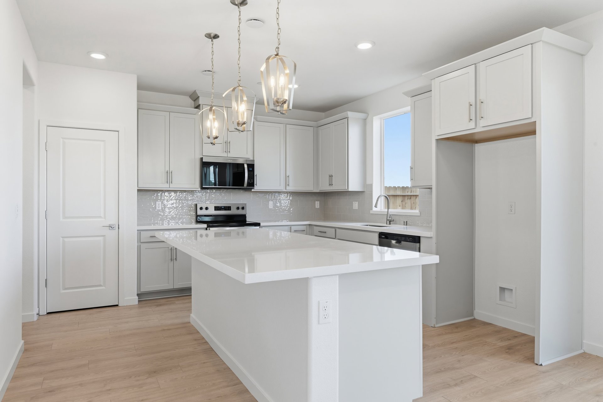 kitchen with white cabinets, white quartz counters, light wood floors, and window above sink