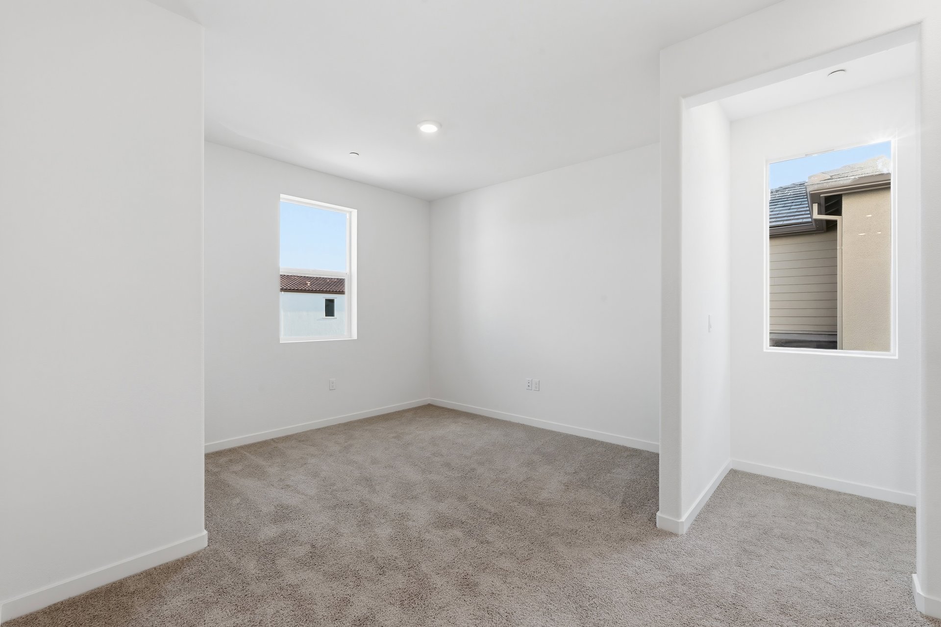 loft with tan carpet, white walls, window, and recessed ceiling light