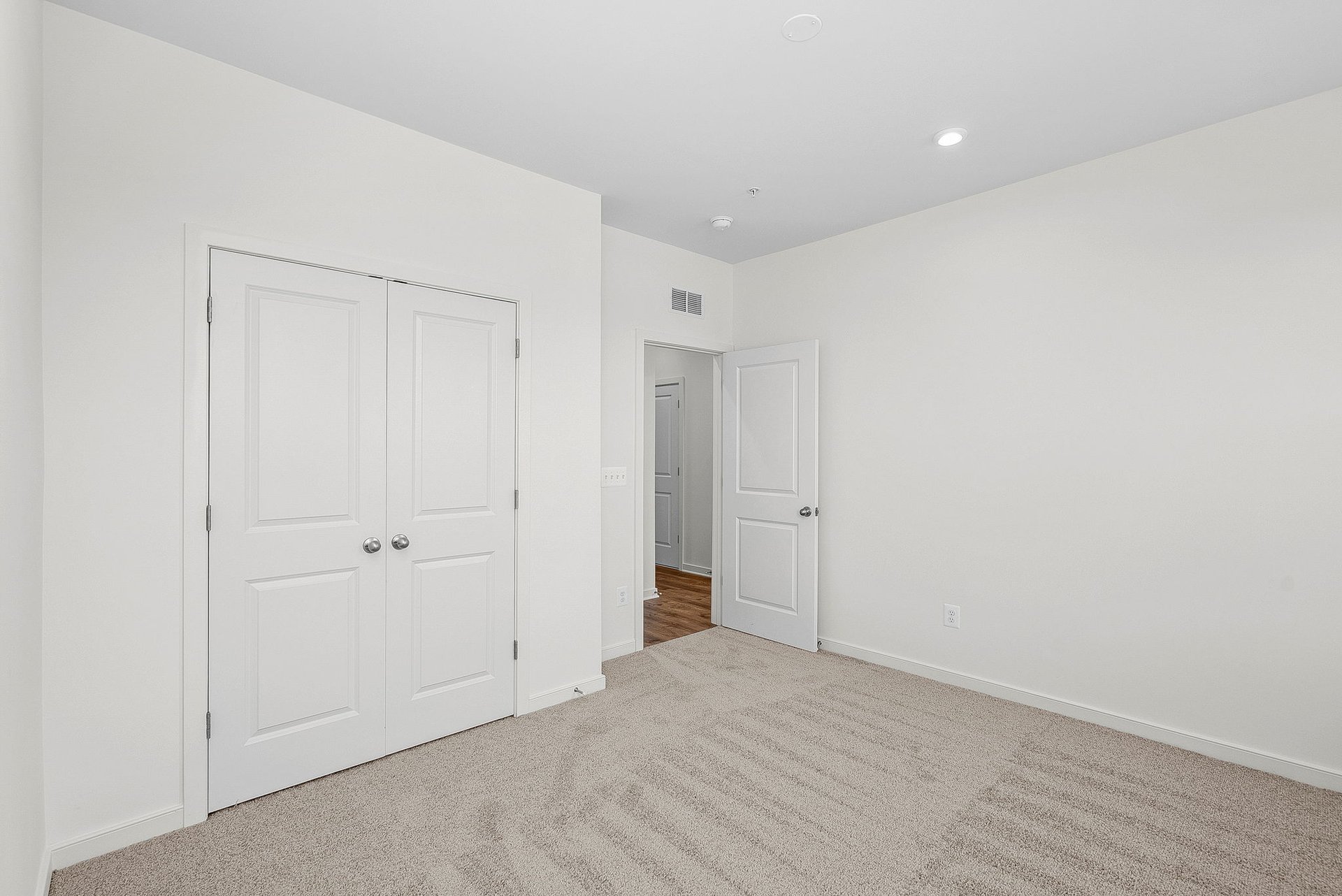 secondary bedroom with closet with two doors and door open to hallway